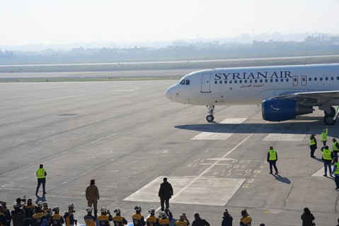 Syrians gather to welcome the first passenger plane to land at Aleppo International Airport