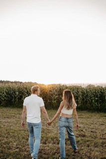 Couple walking hand in hand across a mown field