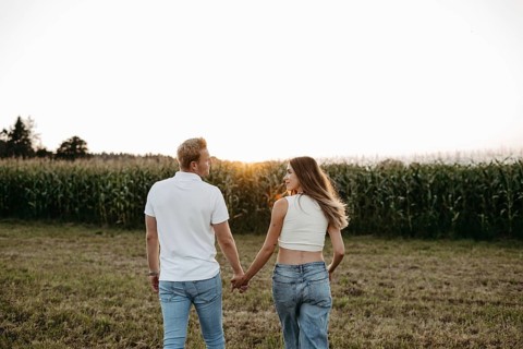 Couple walking hand in hand across a mown field