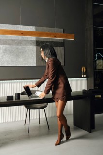 A confident professional woman in formal attire arranges her laptop on a sleek desk in a stylish