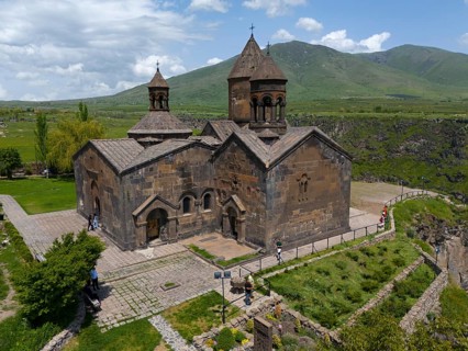 Stone church with natural backdrop and mountain view on paved terrain, aerial view, Saghmosavank