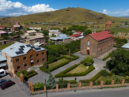 Aerial view of a village with a church and a hill in the background under a blue sky, aerial view,