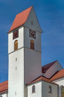 Church tower with gabled roof and clock, parish church of St Lawrence from 1404 in Leupolz in
