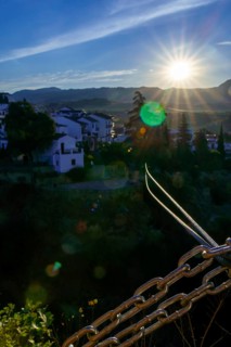 Steel cables and chains stretch towards the picturesque town of ronda, spain, bathed in the golden