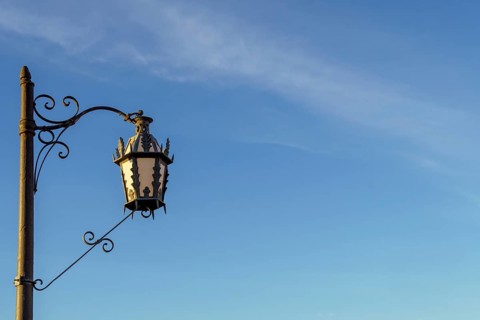 Ornate street lamp with wrought iron detail stands against a clear blue sky in ronda, malaga, spain
