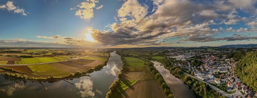 The sunset bathes the river landscape of the Danube in a warm light. A few fields and meadows