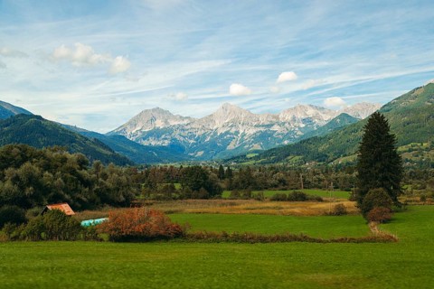 Wide meadows stretch out in front of an alpine mountain range, Haller Mauern, under a clear sky,
