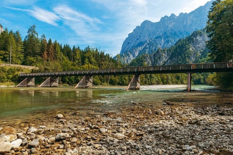 Wooden bridge over the Enns with stony bank and Reichenstein group in the background, Gesäuse,