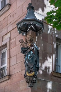 House saint, Mary with the baby Jesus under a canopy, at a residential and commercial building,