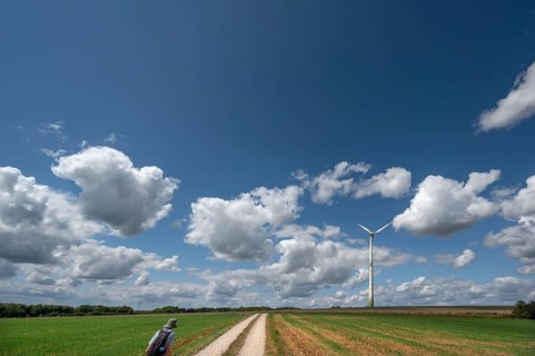 Hiker on a country lane in Franconian landscape, a windmill behind, cloudy sky, Karsberg, Upper