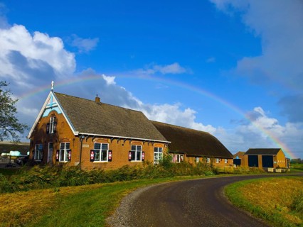A picturesque farm in the countryside with a rainbow over the blue sky, former monastery, farm with