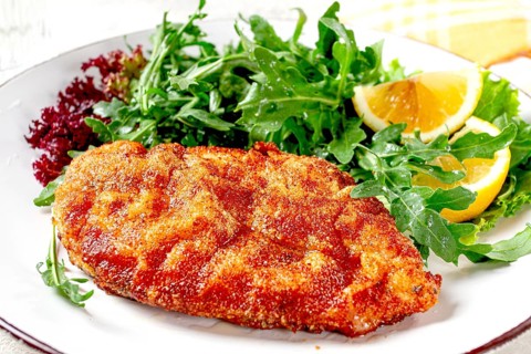 Milanese chicken, Crispy breaded chicken served, with fresh herbs, and lemon wedges