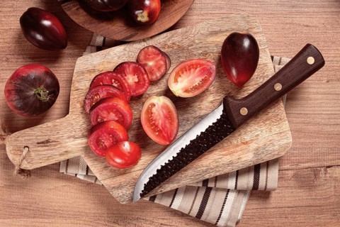 Sliced tomatoes, Black Beauty variety, on a cutting board, top view, on the kitchen table