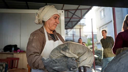 A Turkish woman bakes traditional bread on a clay tandoor oven in a rural village, Hatay, Hatay,