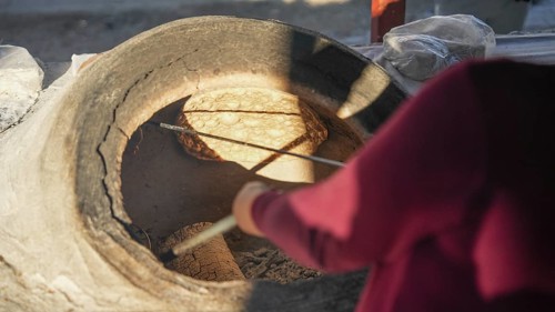 A Turkish woman bakes traditional bread on a clay tandoor oven in a rural village, Hatay, Hatay,