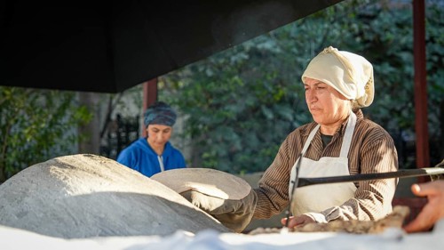A Turkish woman bakes traditional bread on a clay tandoor oven in a rural village, Hatay, Hatay,
