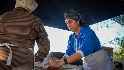 A Turkish woman bakes traditional bread on a clay tandoor oven in a rural village, Hatay, Hatay,