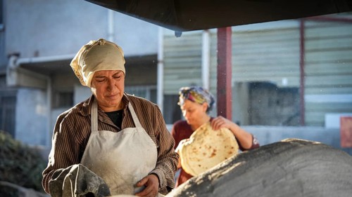A Turkish woman bakes traditional bread on a clay tandoor oven in a rural village, Hatay, Hatay,