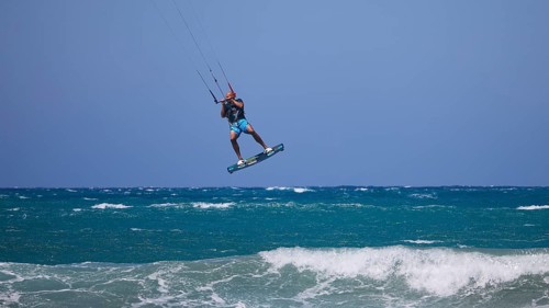 Kitesurfer jumping high over waves under a clear blue sky, Prasonisi, beach, surf, windsurfer, kite
