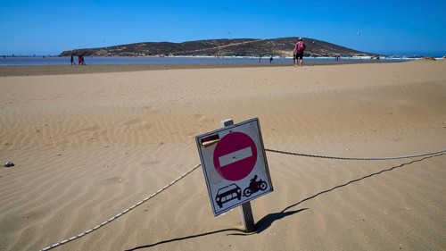 Prohibition sign stands in the sand of a wide beach under a blue sky, Prasonisi, beach, surf,