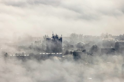 Aerial view, residential area in fog with high-rise building mobile phone antennas in backlight in