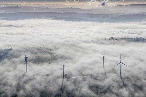 Aerial view, wind turbines in the fog and mountains of the Sauerland in the backlight in the