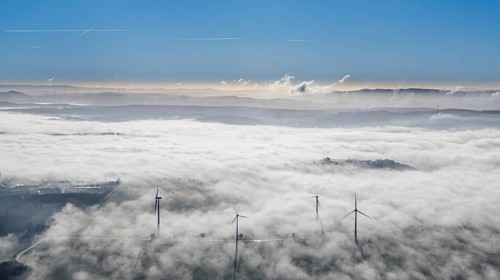 Aerial view, wind turbines in the fog and mountains of the Sauerland in the backlight in the