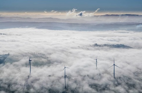Aerial view, wind turbines in the fog and mountains of the Sauerland in the backlight in the