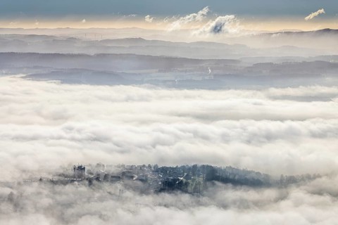 Aerial view, residential area in fog with high-rise building, mobile phone antennas in backlight in