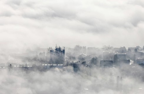 Aerial view, residential area in fog with high-rise building mobile phone antennas in backlight in