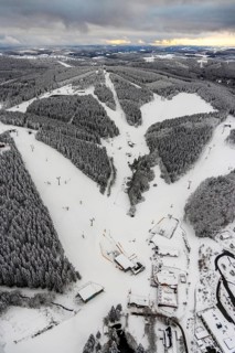 Aerial view of the snowy winter landscape of Winterberg with deserted ski lifts and slopes during