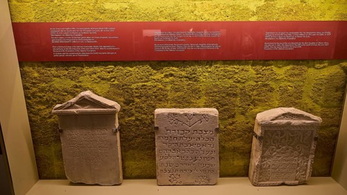 Three ancient Hebrew tombstones in an exhibition with yellow background, Kahal Shalom Synagogue,