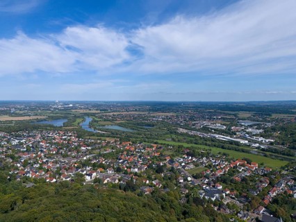 View of a town with river and green landscape under a blue sky with clouds, aerial view from the