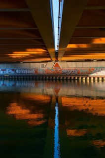 View across the Mittelland Canal to the underside and the graffiti-painted abutment of a bridge on