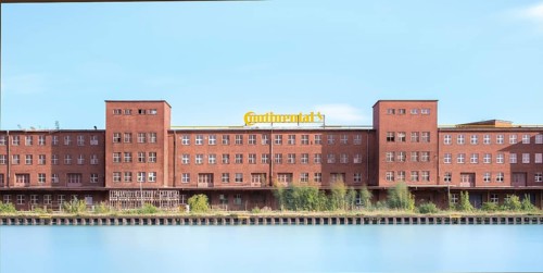 View across the Mittelland Canal to an industrial building with trees growing in front of it, long