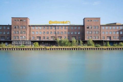 View across the Mittelland Canal to an industrial building with trees growing in front of it, long