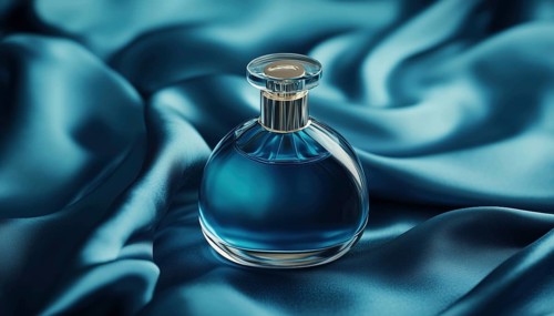 Mock Up Packaging Of Perfume Bottle On Silk Folded Fabric With Dark Blue Liquid. Realistic Scent
