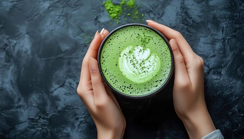 Top View Shot Of Woman Holding A Delicious Matcha Latte In A Dark Gray Background, Captured In A
