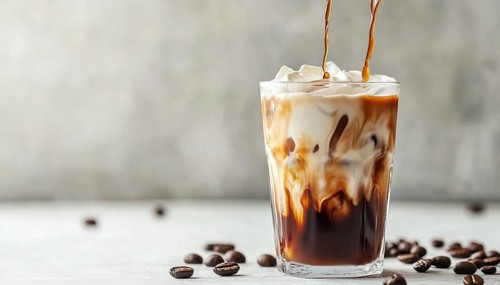 Refreshing Iced Coffee With Cream Being Poured On White Table. Cool And Invigorating Coffee Latte