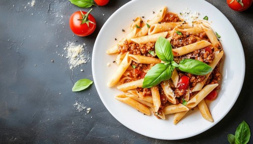 Delicious Penne Pasta With Bolognese Sauce And Basil Served In A White Plate On A Light Background.