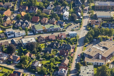 Detailed view of a residential area with many individual houses, streets and green gardens, aerial
