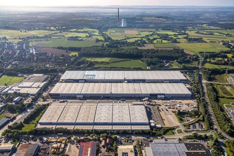 Large area with warehouses in the middle of a rural landscape under a sunny sky, aerial view Werl