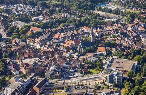 Close-up of the town centre with a prominent church surrounded by houses and green areas, aerial
