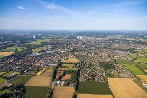 Aerial view of the city with numerous fields and houses under a slightly cloudy sky, aerial view