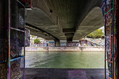View under a bridge with graffiti on the walls over a river, Am Donaukanal Innere Stadt Vienna