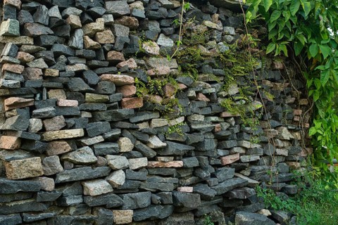 Rough stone wall stacking with overgrown greenery on a side-Dhaka, Bangladesh