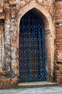 An ornate blue-metal gate set in a rustic old brick archway-Dhaka, Bangladesh