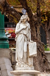 A classic marble statue with a dove on its head, surrounded by autumnal trees and rustic scenery, A