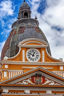 Architecturally richly decorated tower with clock and coat of arms under a cloudy sky, The