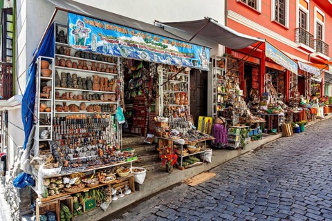 Steep street with shops selling pottery and souvenirs. Colourful facades create a nostalgic market
